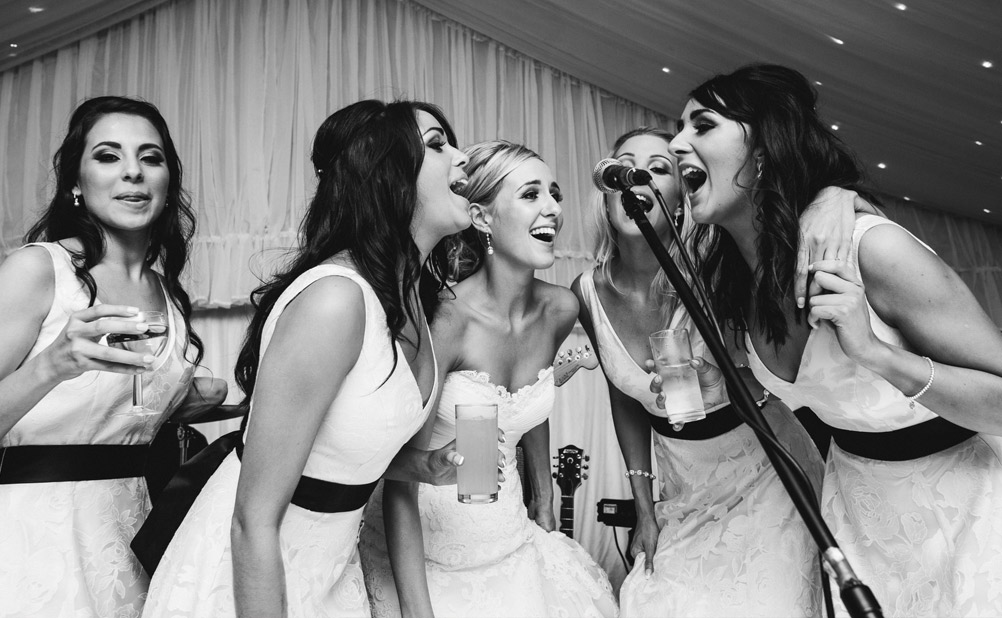 Bride and bridesmaids do karaoke at wedding reception